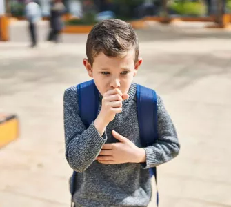 Enfant avec un cartable qui tousse